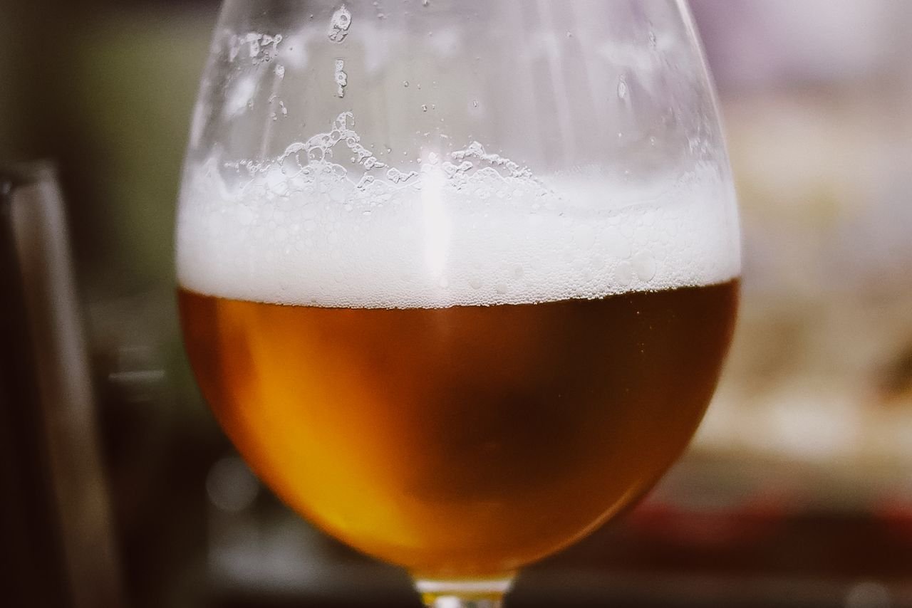 A glass of golden imperial IPA with a thick white foam head, showing the rich color and carbonation of the style