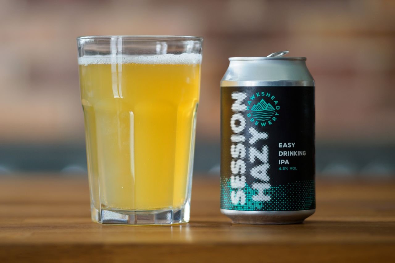 A can of pale ale beside a freshly poured glass showing golden color and white foam head