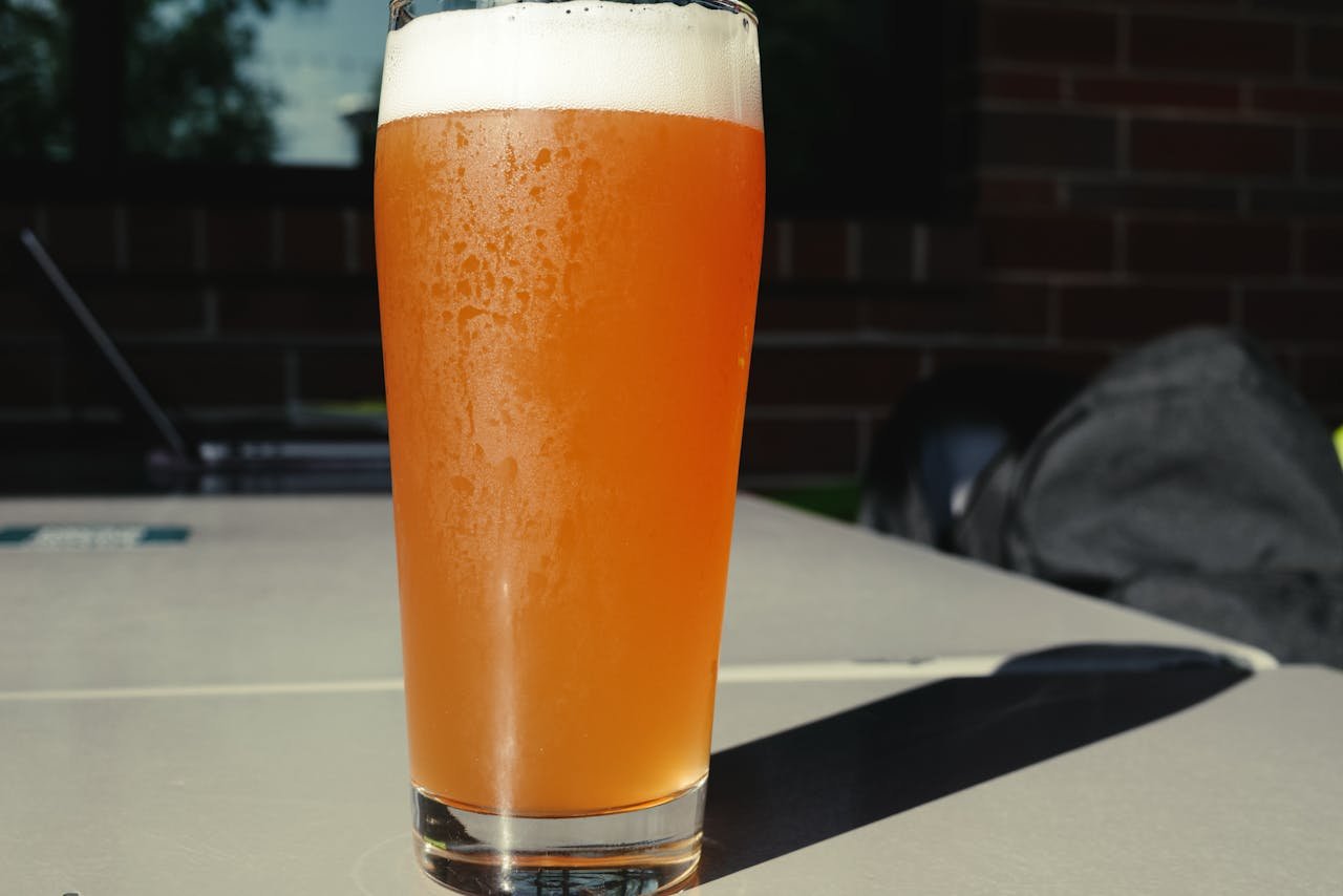 A sunlit pale ale in a pint glass showing hop-derived golden color