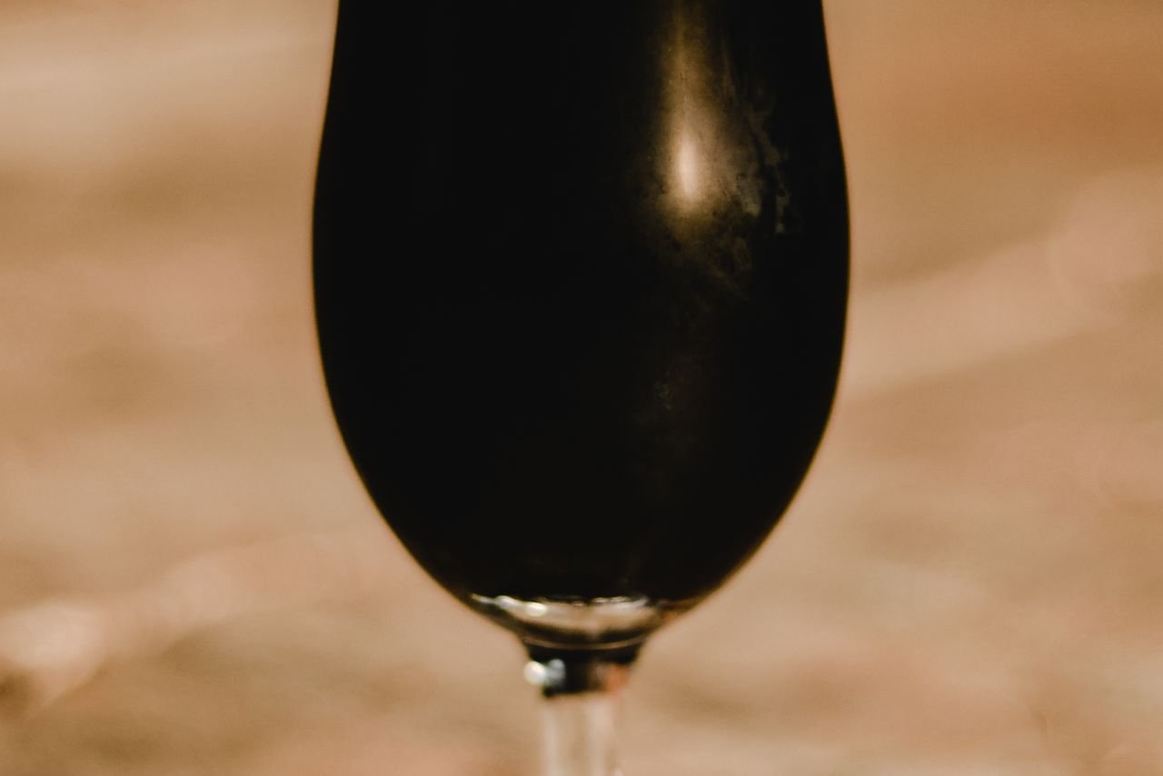 A tulip glass of golden sour beer with a thin white head
