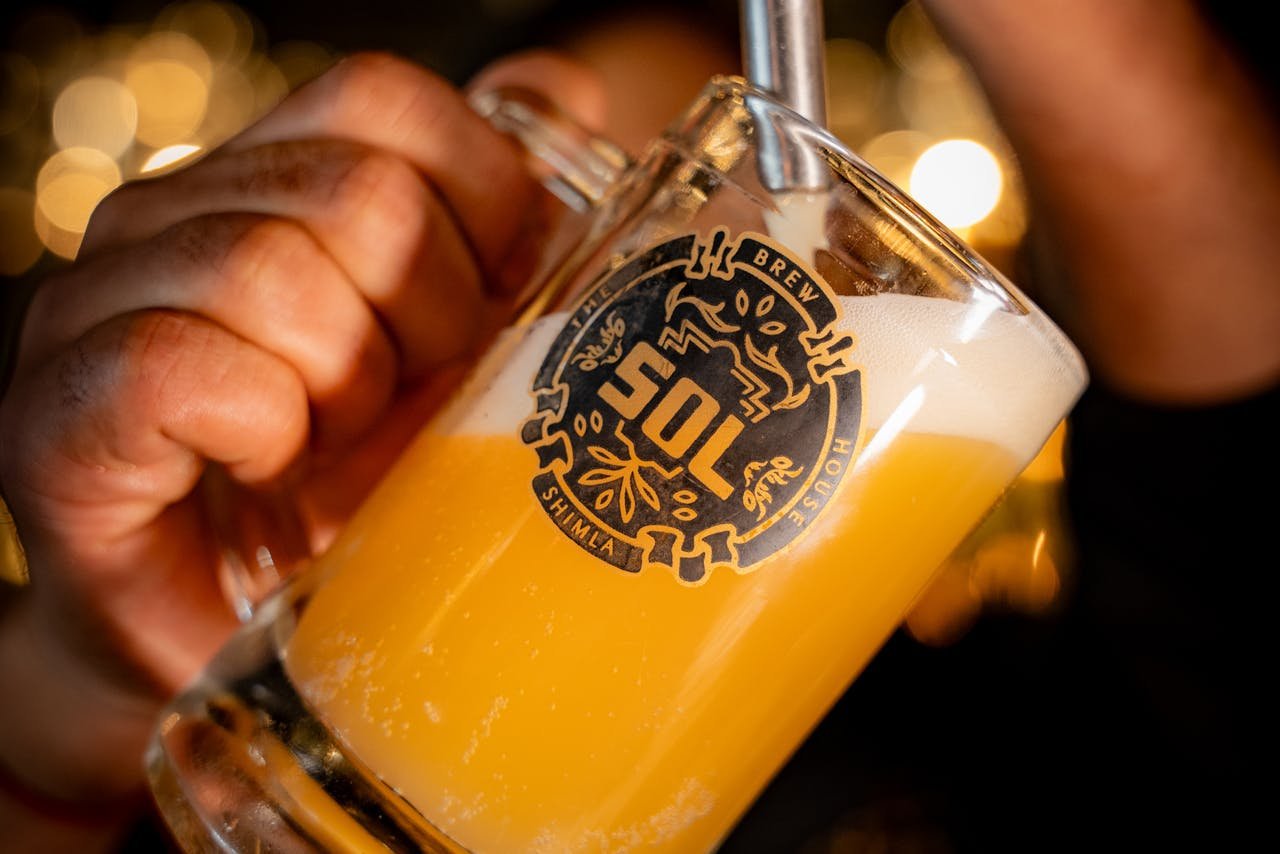 Bartender pouring a pint of golden beer at a tap, with foam building in the glass