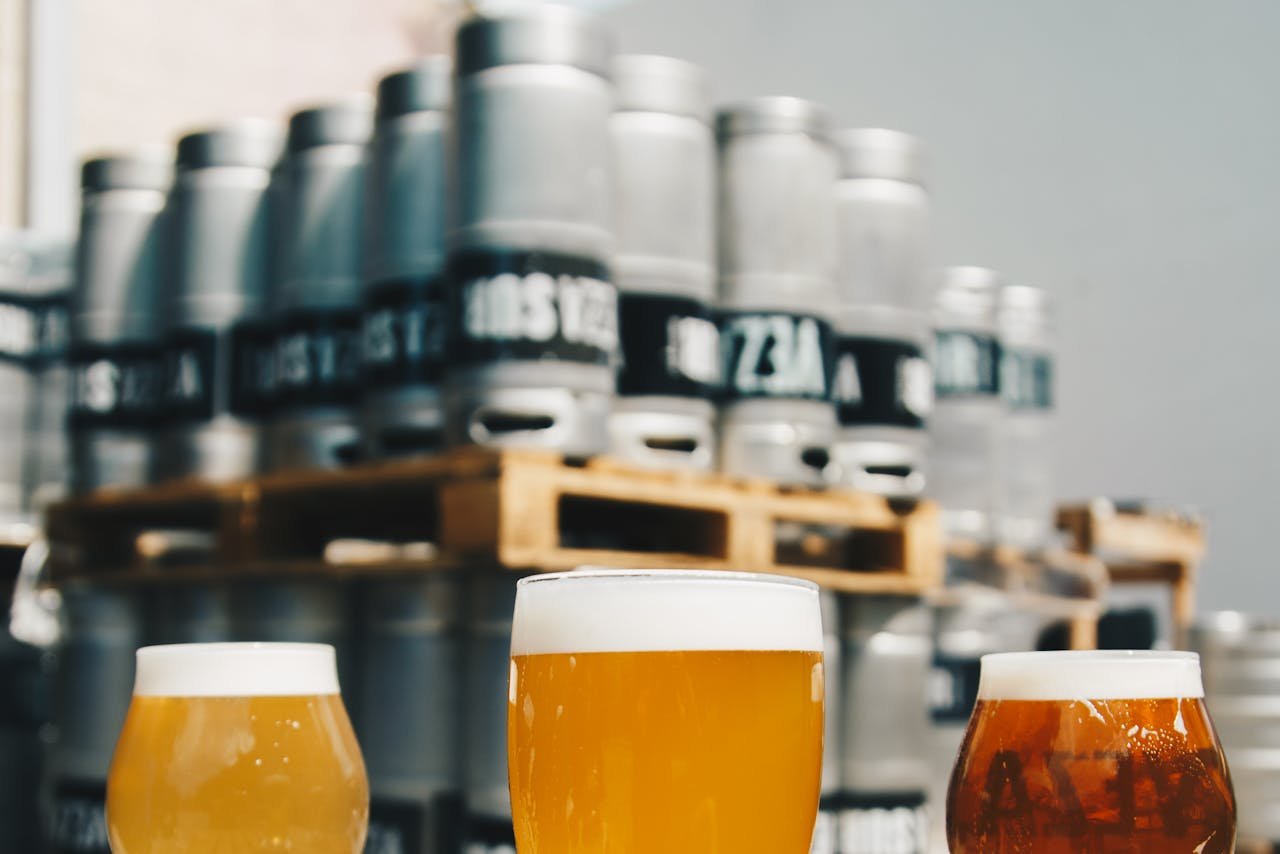 A flight of homebrewed beers in small glasses lined up, varying in color from pale gold to deep amber
