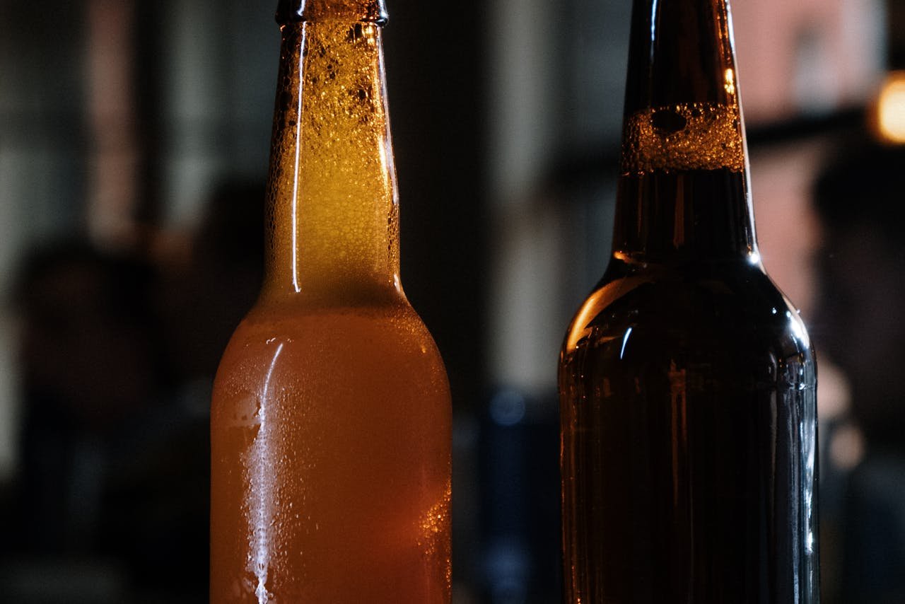 Row of capped brown homebrew bottles lined up on a wooden surface, ready for conditioning