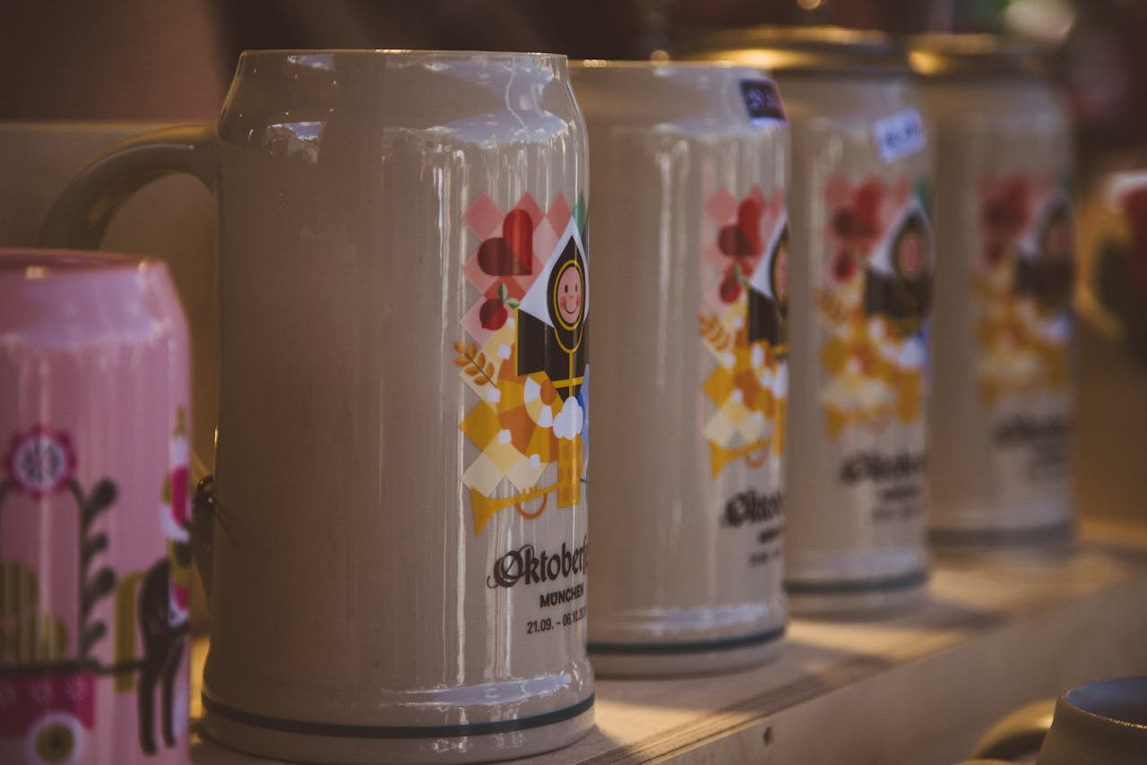 Close-up of several ornate ceramic beer steins arranged on a wooden festival table