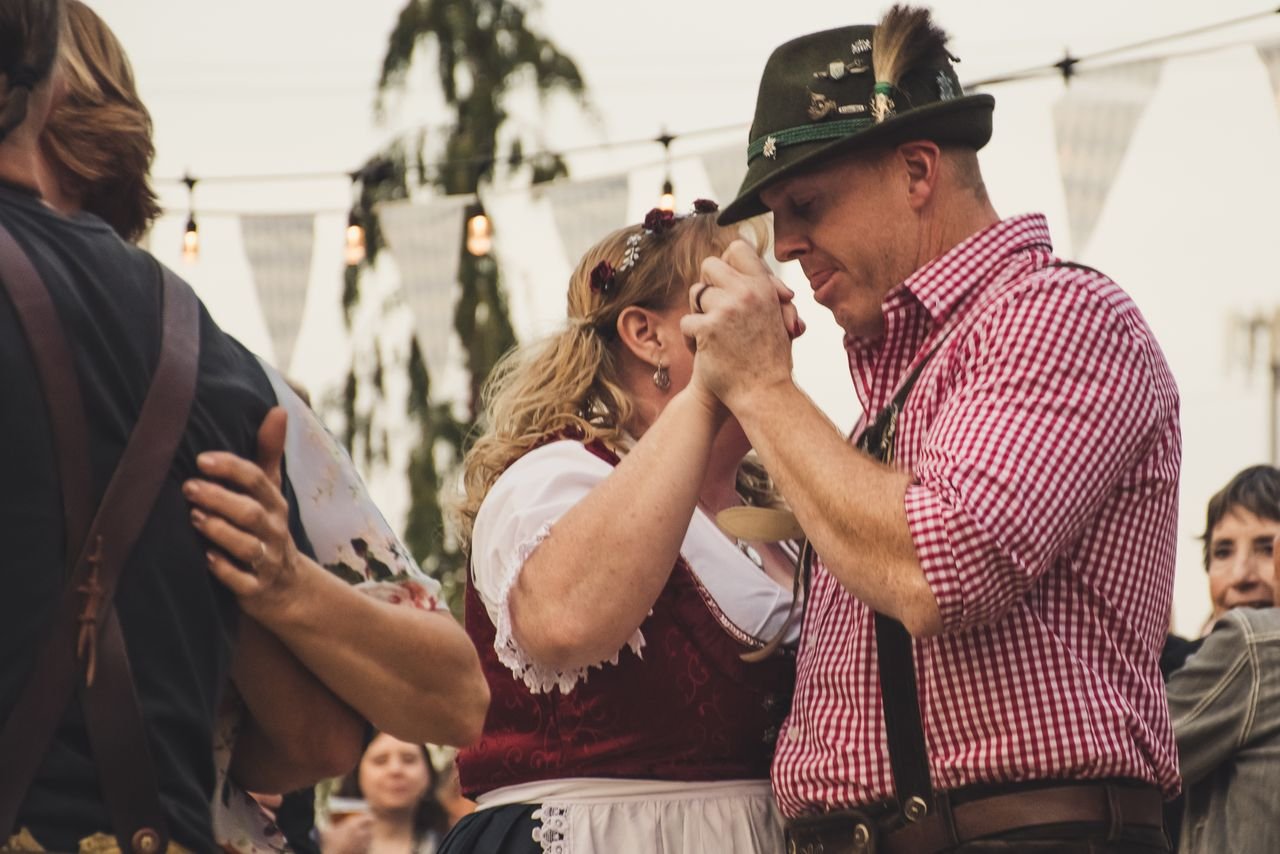 Couple in traditional Bavarian dress dancing joyfully inside a festival tent