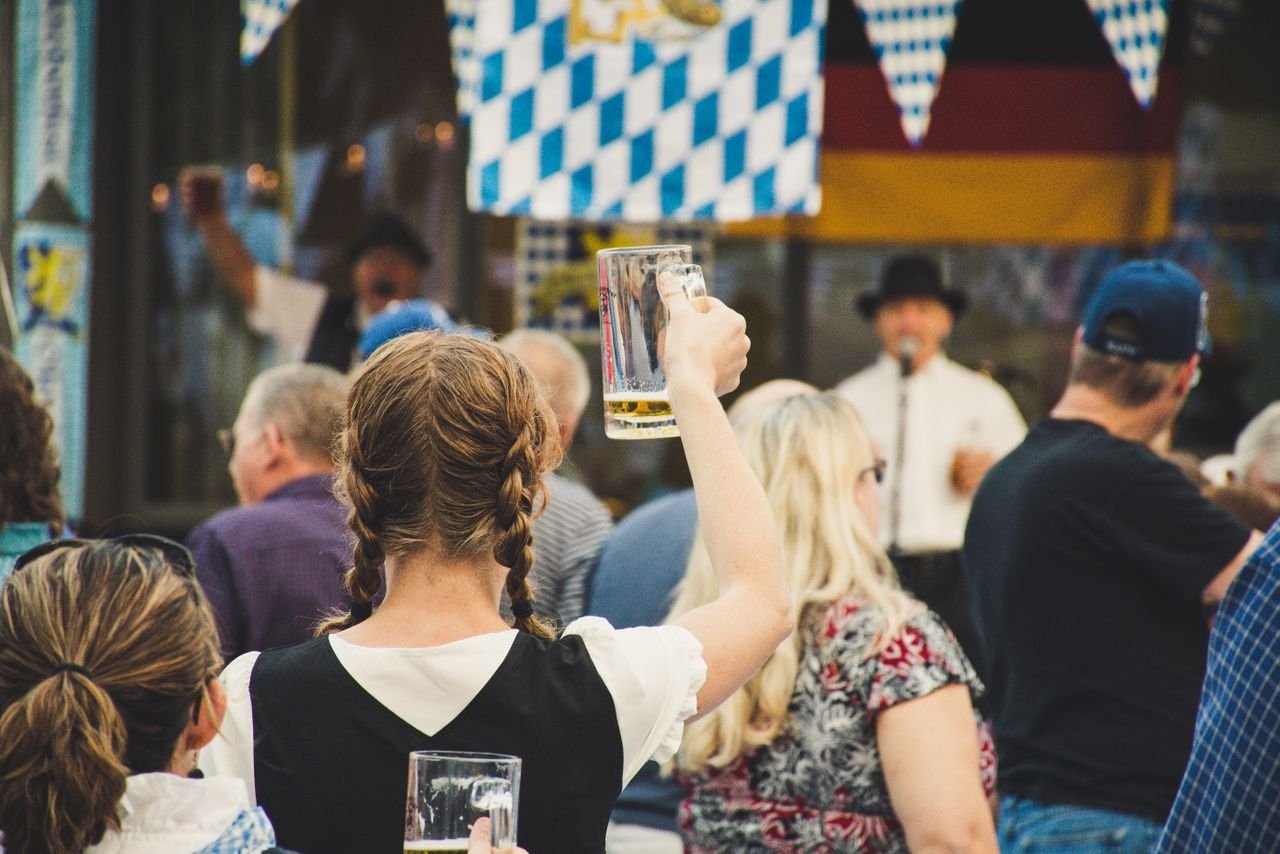 A packed Oktoberfest tent with crowds of people raising full beer steins