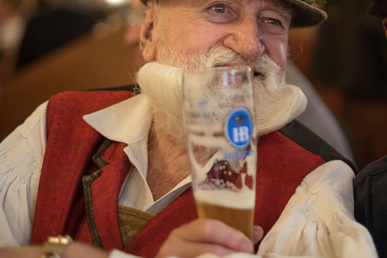 Older gentleman savoring a golden Belgian beer in a tulip glass at a festival