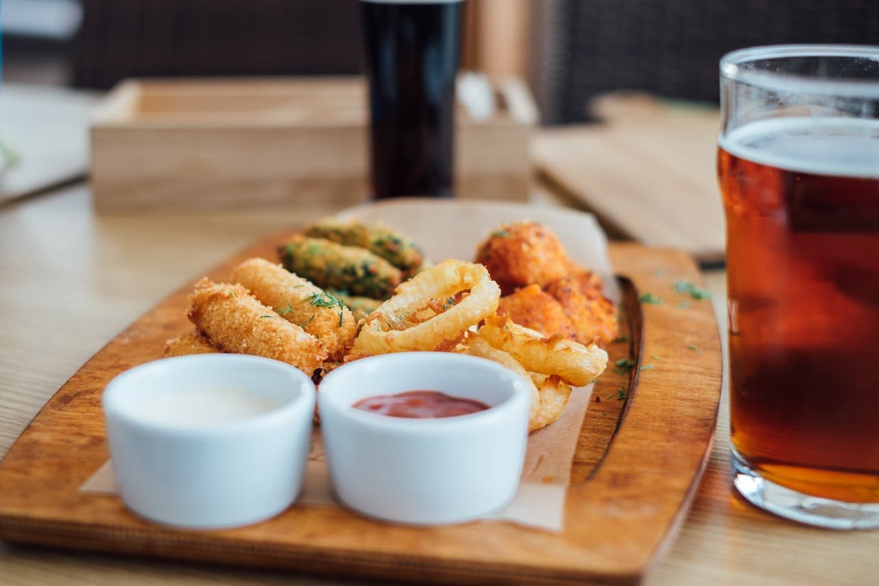 A spread of appetizers with two glasses of beer on a pub table