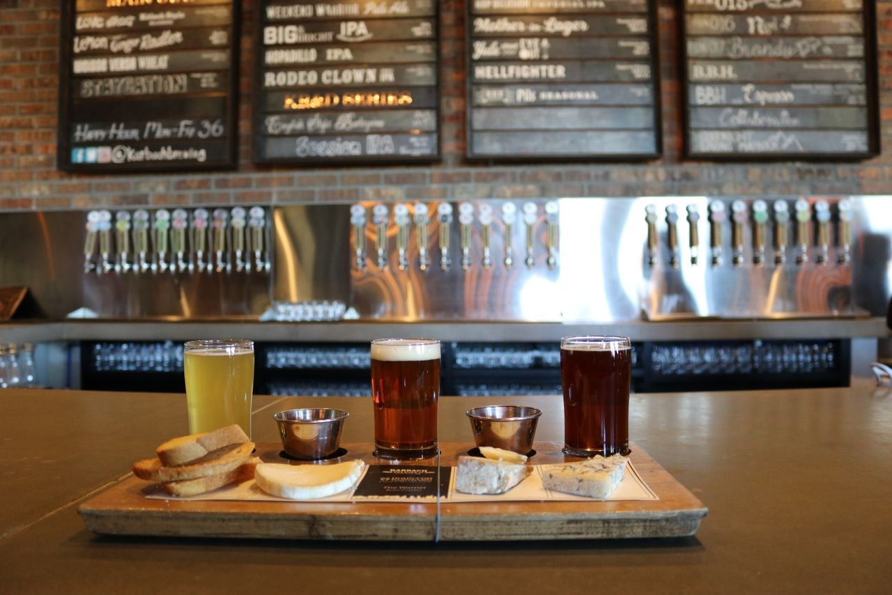 A spread of beer, artisan cheese, and rustic bread on a wooden board