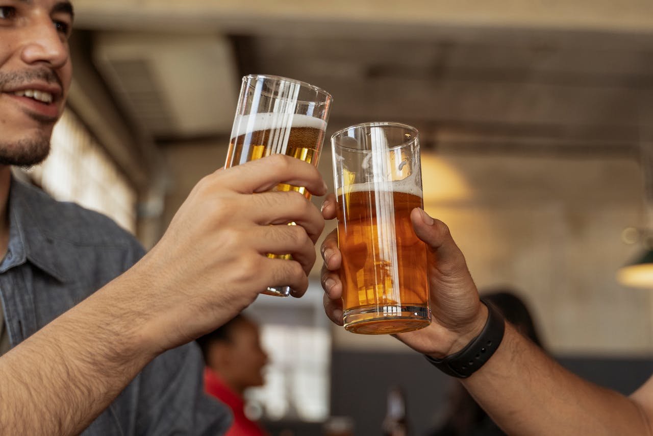 Two elegant stemmed beer glasses clinking together in a toast