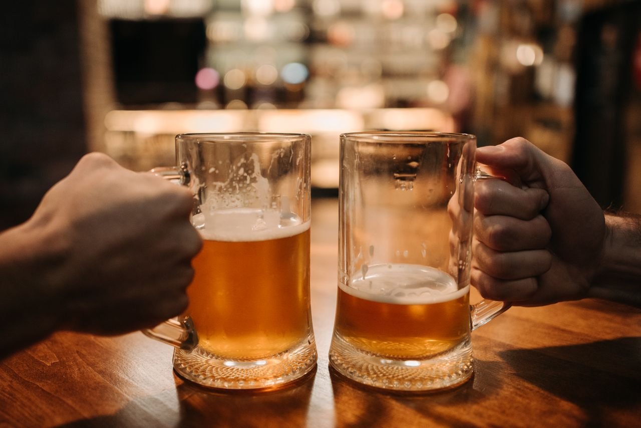 Two large mugs of golden beer clinking together in celebration