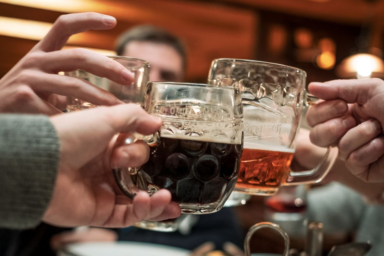 Friends raising glass mugs in a warm, well-lit pub setting
