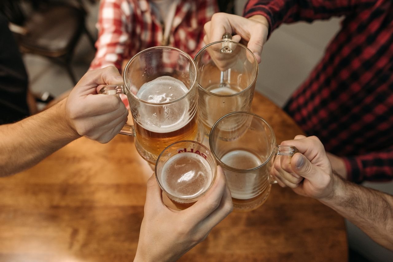 A group raising ceramic beer mugs in a toast at a pub
